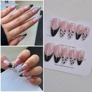 Details von rosa Mandel-Nägeln mit schwarzen French-Tips, 3D-Schmetterlingen und Strass