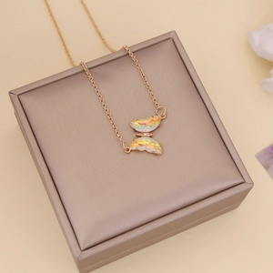 Close-up of golden butterfly necklace with iridescent crystal on jewelry box