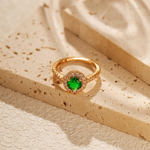 Detail of 18K gold plated ring with green zircon centerpiece and pavé halo design