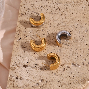 Detail showing two-tone gold and silver C-shape hoop earrings on a marble display