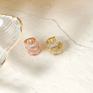 Elegant gold and rose gold hoop earrings with sparkling cubic zirconia on marble background