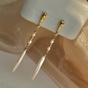 Detailed close-up of Baroque freshwater pearl tassel earrings on champagne silk fabric