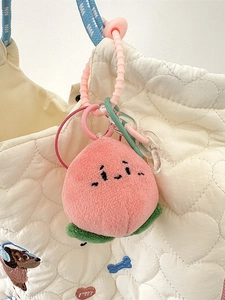 Porte-clés pêche en peluche avec visage suspendu sur un sac à main blanc matelassé