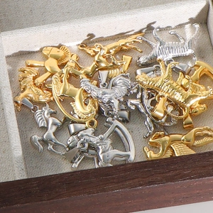Detailed pile of gold and silver stainless steel animal pendants in a wooden jewelry box