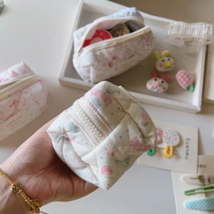 Détail du petit sac matelassé en coton à fleurs avec fermeture éclair et texture douce