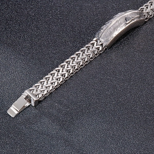 Detail of silver feather charm on hip hop steel bracelet with double braided chain