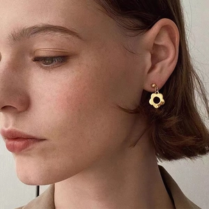 Close-up of elegant gold flower drop earrings worn by a model in soft lighting