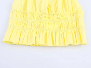 Detailed close-up of yellow halter top featuring elastic pleated hem and ruffled edges