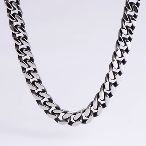 Macro view of polished silver Cuban link chain with detailed black oxidized finish