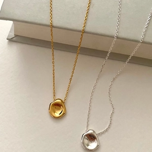 Macro detail of gold and silver irregular lava pendant necklaces on vintage books
