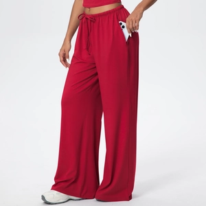 Detail of red wide-leg lounge pants showing the drawstring waist and side pocket with phone