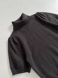 Detail of dark charcoal knit top showing ribbed neckline and subtle puff sleeve texture