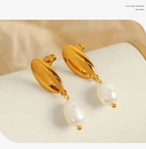 Detailed close-up of 18K gold crescent hoop earrings with hanging white freshwater pearls