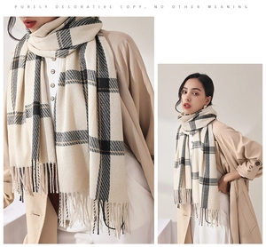 Vue détaillée d'une écharpe à carreaux beige avec motif classique et pompons à franges