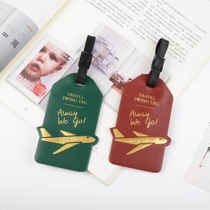 Green and red PU leather airplane luggage tags with gold travel quotes on a magazine