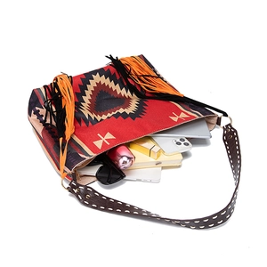 Detail of bohemian woven tote bag with geometric patterns, orange tassels and leather strap