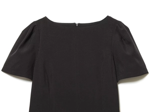 Detailed view of the off-shoulder neckline and puff sleeves on a black pleated dress