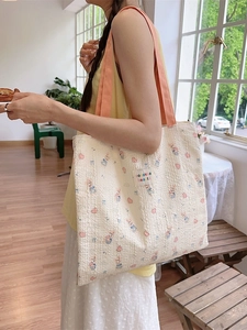 Floral bunny tote bag with textured fabric and orange straps shown in a cozy cafe setting