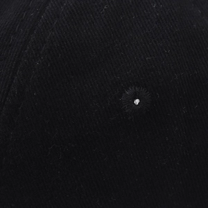 Detailed macro view of embroidered ventilation eyelets on the black twill fabric of the cap