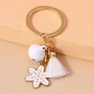 Detailed shot of Christmas keychain with white snowflake charm, bell and tassel detail