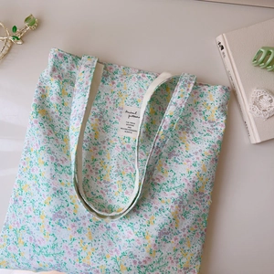 Detail of floral canvas tote bag with green pastel patterns and fabric brand label