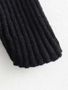 Close-up detail of black ribbed knit sweater dress sleeve showing fine texture and fabric