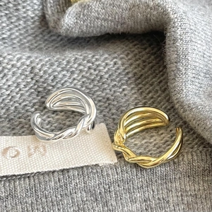 Macro shot of gold and silver irregular layered open rings on grey knit fabric