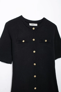 Detailed flat lay of a black knit cardigan featuring elegant gold buttons and round neck