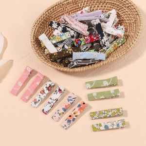 Detailed macro shot of assorted floral fabric wrapped hair clips in a woven basket