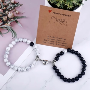 Close-up of magnetic heart couples bracelets with black and white beads on a promise card