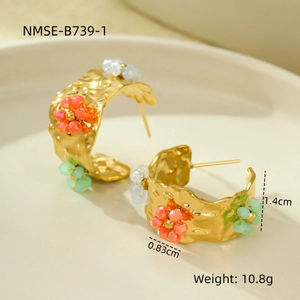 Macro view of C-shaped textured 18K gold earrings with colorful bead flower details