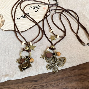 Close-up of vintage bronze butterfly and camera pendants with wooden beads on wax cord