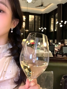 Close-up of pearl flower earrings with opal stones on a model in a restaurant setting