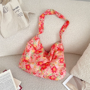 Detail of floral hobo shoulder bag with bright flower patterns on a soft fabric texture