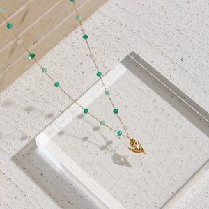 Détail macro du collier pendentif tulipe avec perles colorées sur fond de pierre