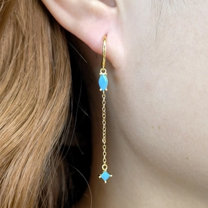 Detail von goldenen Ohrhängern mit blauen Marquise-Kristallen an einem Model