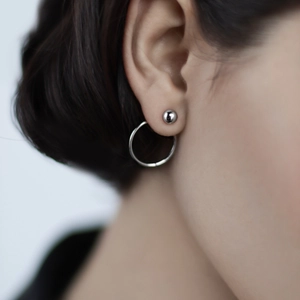 Close-up of minimalist 925 sterling silver ball and hoop earrings worn on an ear