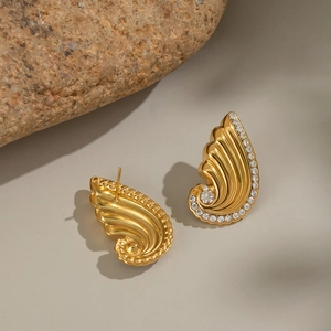 Macro shot of gold shell earrings featuring a polished surface and crystal accents