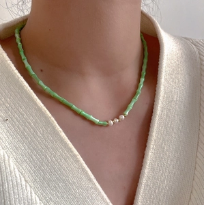 Detailed close-up of light green bamboo beads and white pearls on the necklace