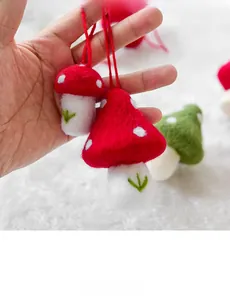 Close-up of handmade wool felt mushroom ornaments with red hanging string and soft texture