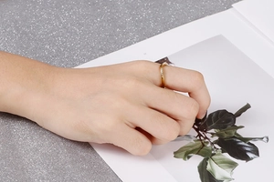 Détail d'une bague dorée ondulée ornée de zircons blancs portée à la main d'un mannequin