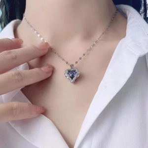 Silberne Herzkette mit blau-violettem Kristall-Anhänger getragen von Model in weißem Hemd