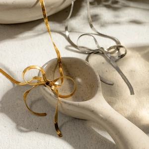 Detail of 18k gold and silver stainless steel flat snake chain bow earrings set