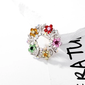 Detailed close-up of a multicolor crystal flower wreath brooch with silver metal base
