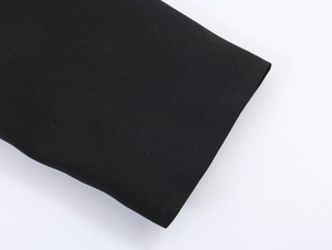 Close-up of the sharp fabric texture and peplum blazer sleeve cuff in solid black