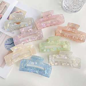 Flat lay of macaron marble acetate hair clips in eight pastel colors on white desk