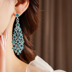 Primer plano de pendientes de plata con cristales de circonita azul en la oreja