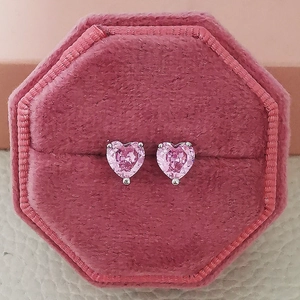 Detailed close-up of pink heart-shaped zircon earrings in a pink velvet jewelry box