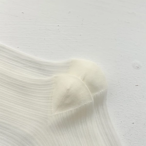 Detailed close-up of white ribbed knit ballet style socks with reinforced heel stitching
