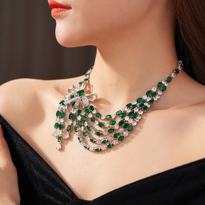 Détail du collier à nœud avec pierres émeraude et blanches sur robe élégante